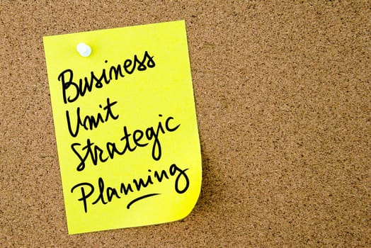Business Unit Strategic Planning text written on yellow paper note pinned on cork board with white thumbtack. Business concept image with copy space available