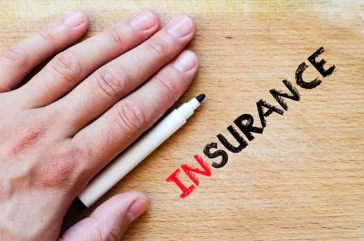 Human hand over wooden background and insurance text concept