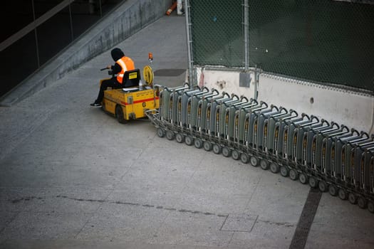 Los Angeles,United States - December 28,2015: An airport employee of LAX Airport pulls a vehicle baggage cart up a ramp in Los Angeles on December 28,2015.