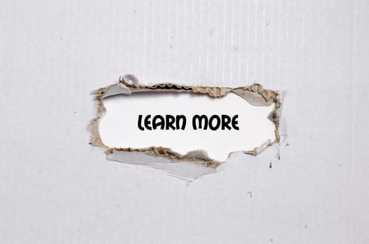 The word learn more appearing behind torn paper