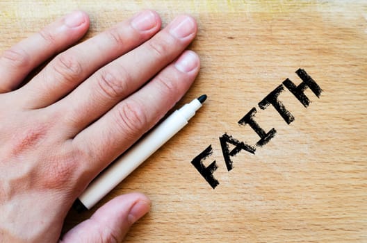 Human hand over wooden background and faith text concept