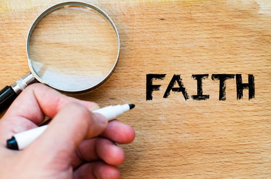 Human hand over wooden background and faith text concept