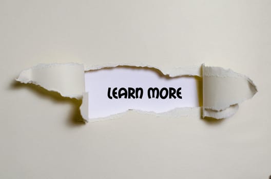 The word learn more appearing behind torn paper