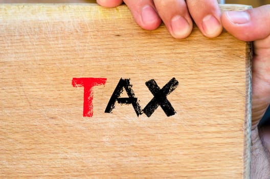 Human hand over wooden background and tax text concept
