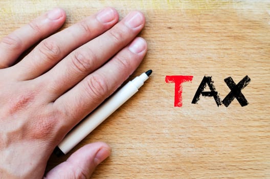 Human hand over wooden background and tax text concept