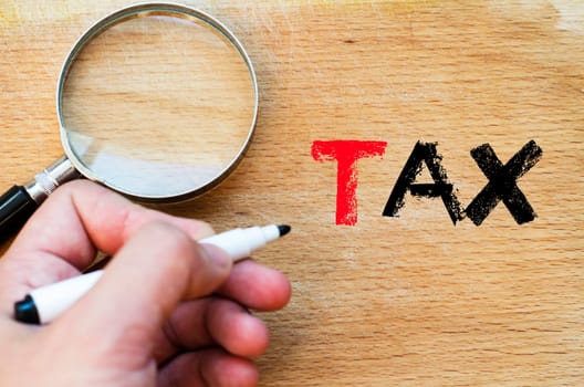 Human hand over wooden background and tax text concept