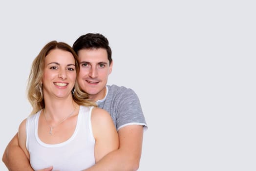young couple in an embrace in front of white background