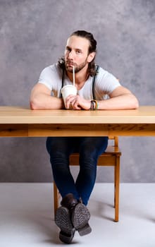 young man drinking soft drink in front of gray background