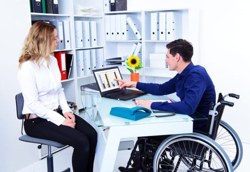 disabled businessman in wheelchair and his female colleague