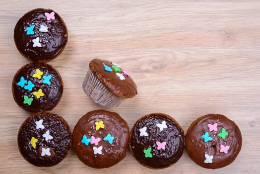 chocolate muffins with colorful decoration on wooden ground