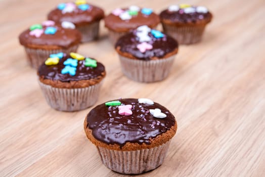 chocolate muffins with colorful decoration on wooden ground