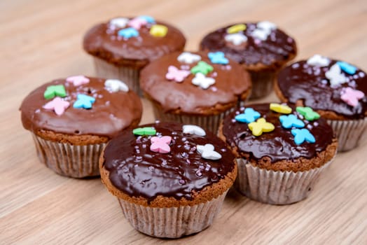 chocolate muffins with colorful decoration on wooden ground