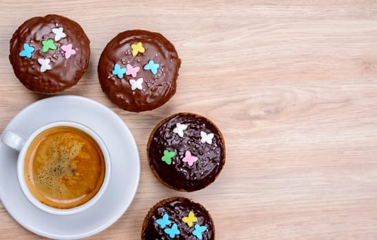 chocolate muffins with cup of coffee on wooden ground