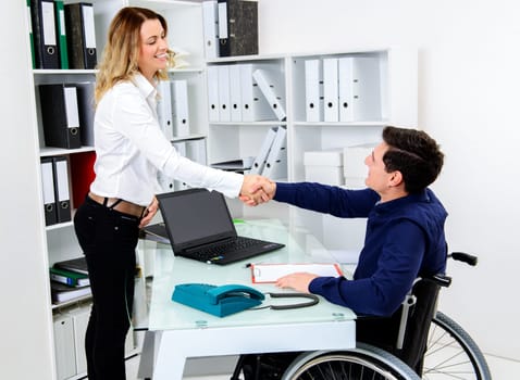 disabled businessman in wheelchair greeting his female colleague