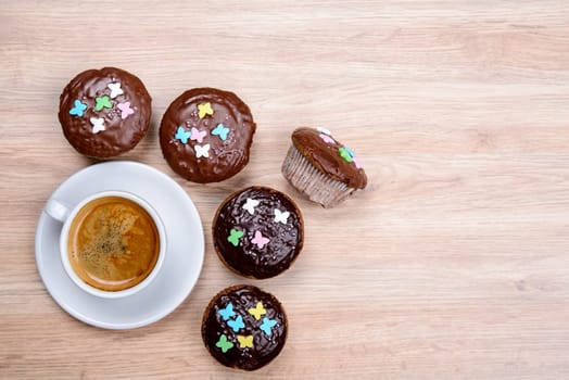 chocolate muffins with cup of coffee on wooden ground
