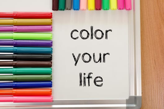 Felt-tip pen and whiteboard on a wooden background and color your life text concept