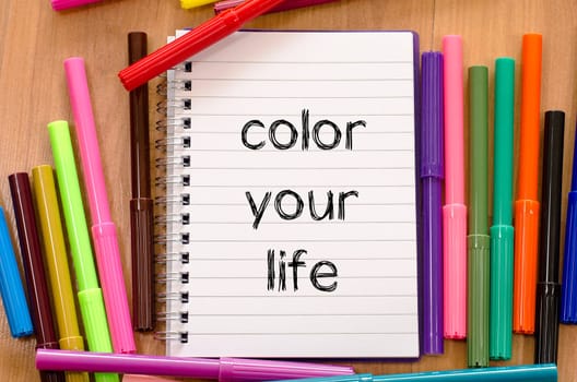 Felt-tip pen and notepad on a wooden background and color your life text concept