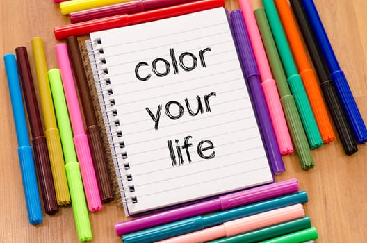 Felt-tip pen and notepad on a wooden background and color your life text concept