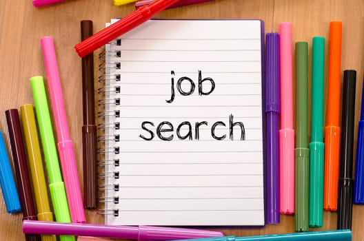 Felt-tip pen and notepad on a wooden background and job search text concept