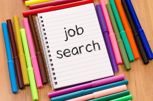 Felt-tip pen and notepad on a wooden background and job search text concept