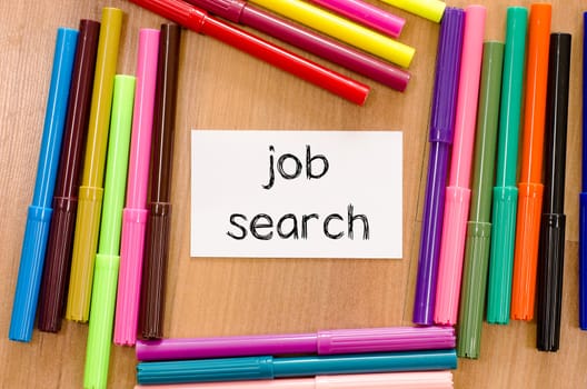 Felt-tip pen and note on a wooden background and job search text concept