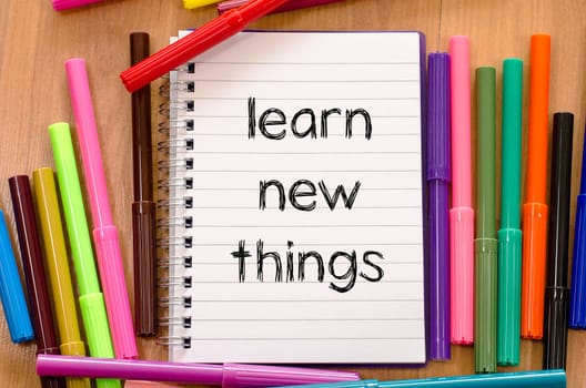 Felt-tip pen and notepad on a wooden background and learn new things text concept