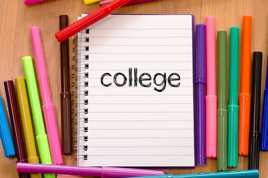 Felt-tip pen and notepad on a wooden background and college text concept