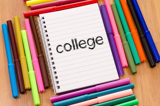 Felt-tip pen and notepad on a wooden background and college text concept