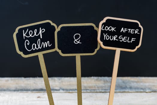Keep Calm and Look After Yourself message written with chalk on mini blackboard labels, defocused chalkboard and wooden table in background. Fun and humor concept