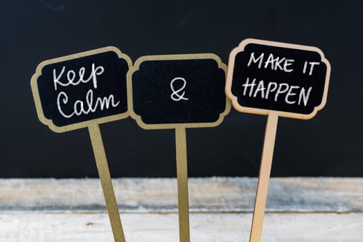 Keep Calm and Make It Happen message written with chalk on mini blackboard labels, defocused chalkboard and wooden table in background. Fun and humor concept