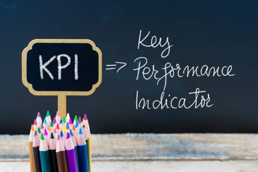 Business Acronym KPI Key Performance Indicator written with chalk on wooden mini blackboard labels and chalkboard background.