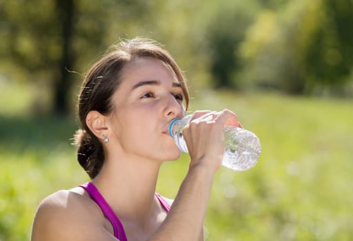 beautiful athletic girl drinking water after exercising