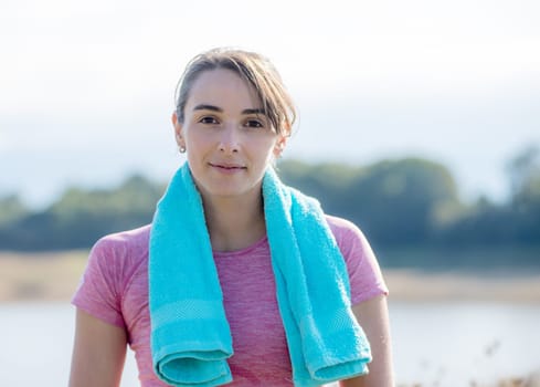 portrait of young sporty woman with blue towel in the countryside