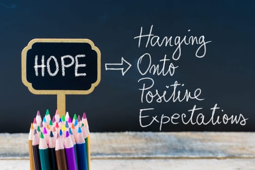 Business Acronym HOPE Hanging Onto Positive Expectations written with chalk on wooden mini blackboard labels and chalkboard background.