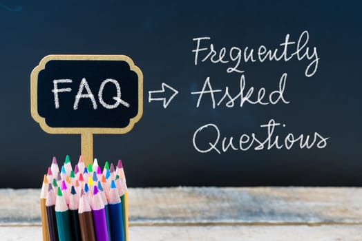 Business Acronym FAQ Frequently Asked Questions written with chalk on wooden mini blackboard labels and chalkboard background.