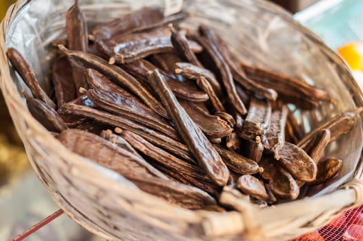 Carob pods in wicker basket. Selective focus.