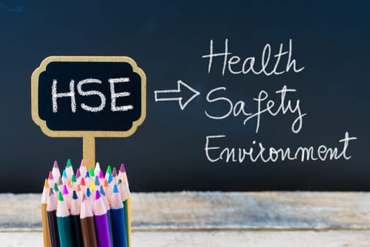 Business Acronym HSE Health Safety Environment written with chalk on wooden mini blackboard labels and chalkboard background.