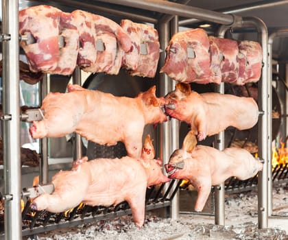 Carcasses of pork and other meat prepared on skewer. Cooking on grill and fire.