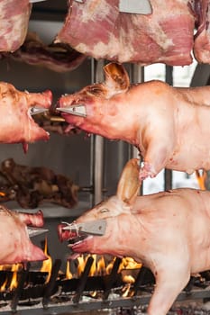 Carcasses of pork and other meat prepared on skewer. Cooking on grill and fire.