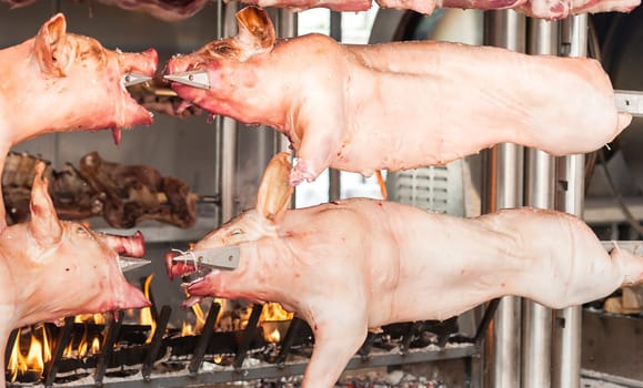 Carcasses of pork and other meat prepared on skewer. Cooking on grill and fire.