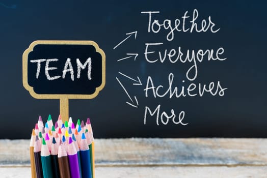 Business Acronym TEAM Together Everyone Achieves More written with chalk on wooden mini blackboard labels and chalkboard background.