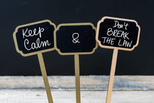 Keep Calm and Do Not Break The Law message written with chalk on mini blackboard labels, defocused chalkboard and wooden table in background. Fun and humor concept