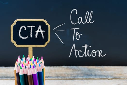 Business Acronym CTA Call To Action written with chalk on wooden mini blackboard labels and chalkboard background.