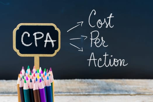 Business Acronym CPA Cost Per Action written with chalk on wooden mini blackboard labels and chalkboard background.