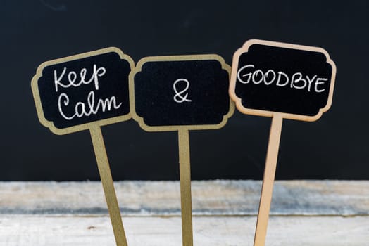 Keep Calm and Goodbye message written with chalk on mini blackboard labels, defocused chalkboard and wooden table in background. Fun and humor concept