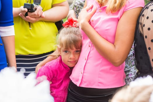 Five-year girl standing in the crowd and clung to her mother