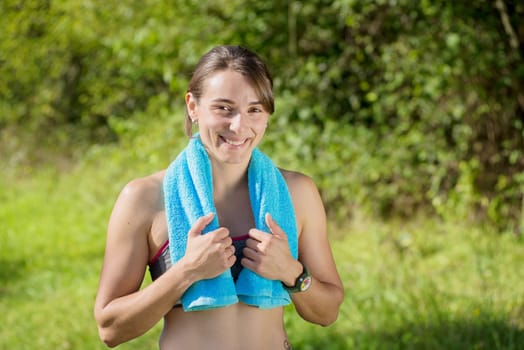 portrait of young sporty woman with blue towel in the countryside