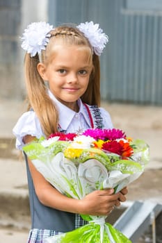 Up portrait of a seven-year school girl with a bouquet of flowers