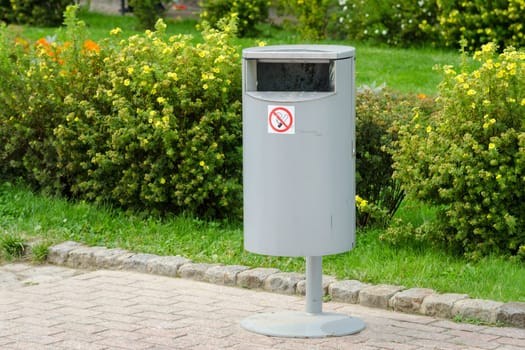Accurate cylindrical metal rubbish bin on a background of a well-kept lawn