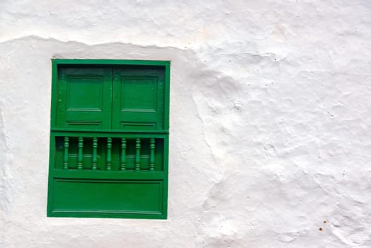 Green window on an old white colonial wall in Barichara, Colombia